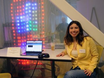 Addie Siembieda sitting by a laptop with her project, "Soundtrack of Our Lives: The Stories."